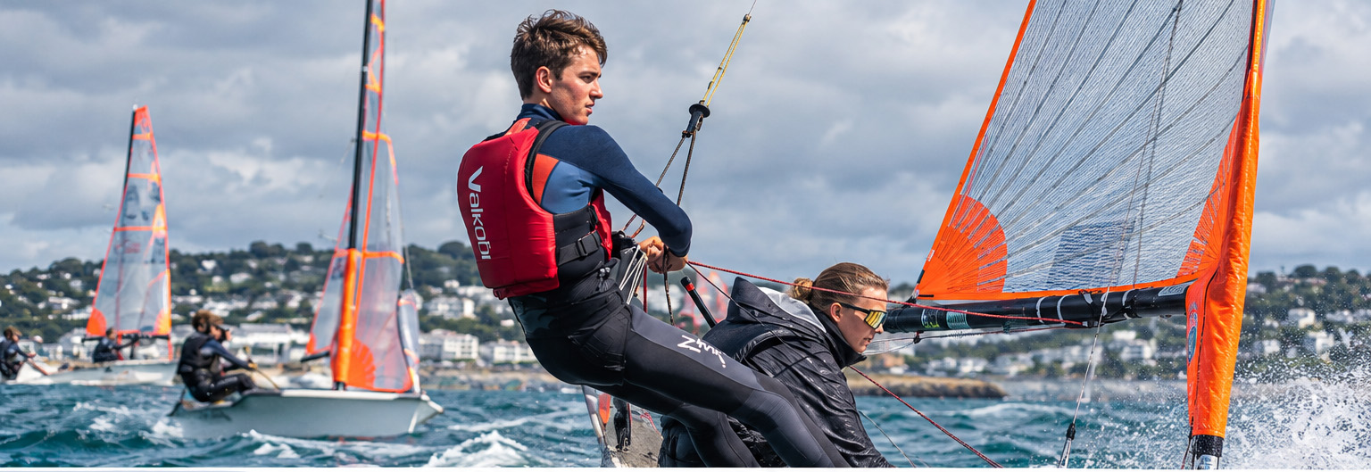 Two dinghy sailors racing in winter conditions wearing wetsuits and protective sailing clothing