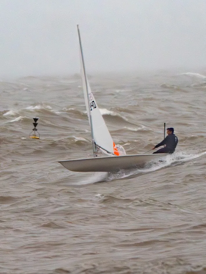 Dinghy sailor racing through rough winter water